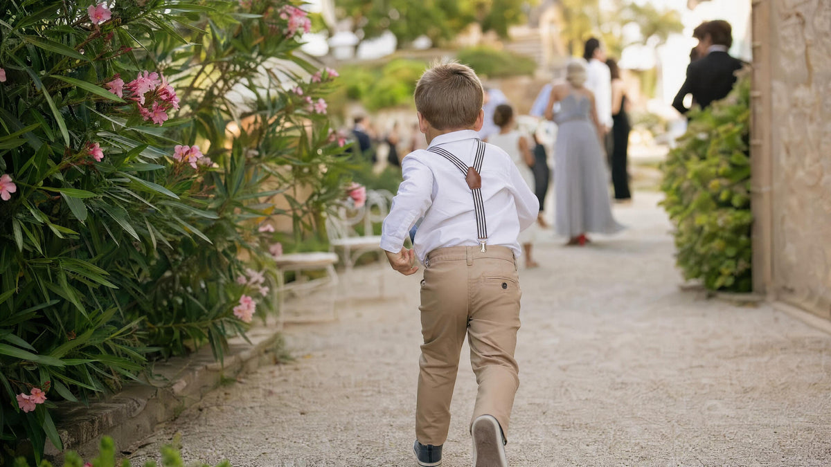 Enfant portant des bretelles pour une cérémonie, tenue élégante et naturelle. Imagem